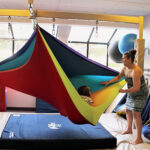 An occupational therapist works with a client using the Pit Pillow as a protective mat.
