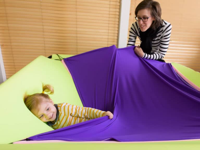 A parent supervises a child playing in the Boundex Cuddle Box.
