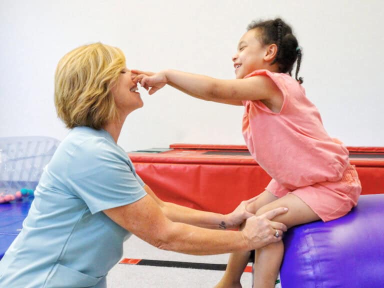 A therapist works with a client on an air barrel.