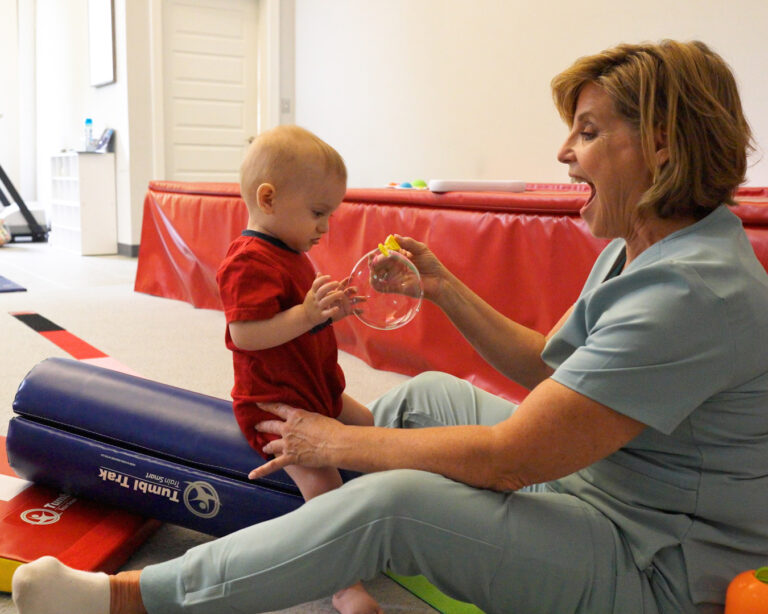 A child balances on a Half Round while working with a therapist.