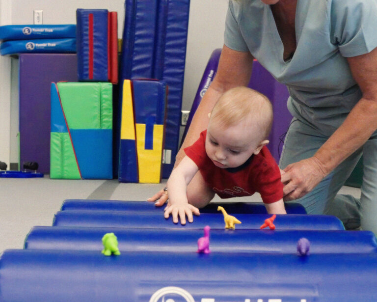 Assisted by his therapist, a child climbs over a series of Half Rounds