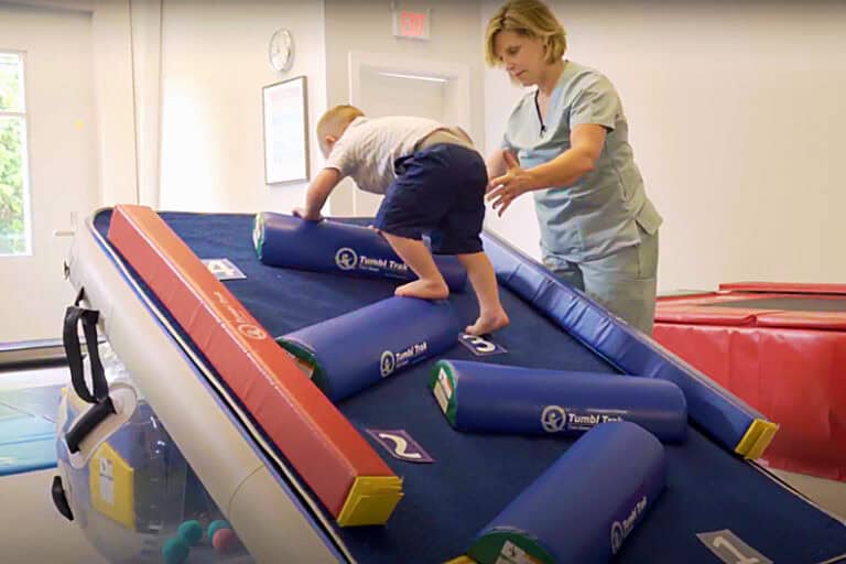 A photo showing a therapist and toddler client using Half Rounds on a Carpet Wall Overlay.