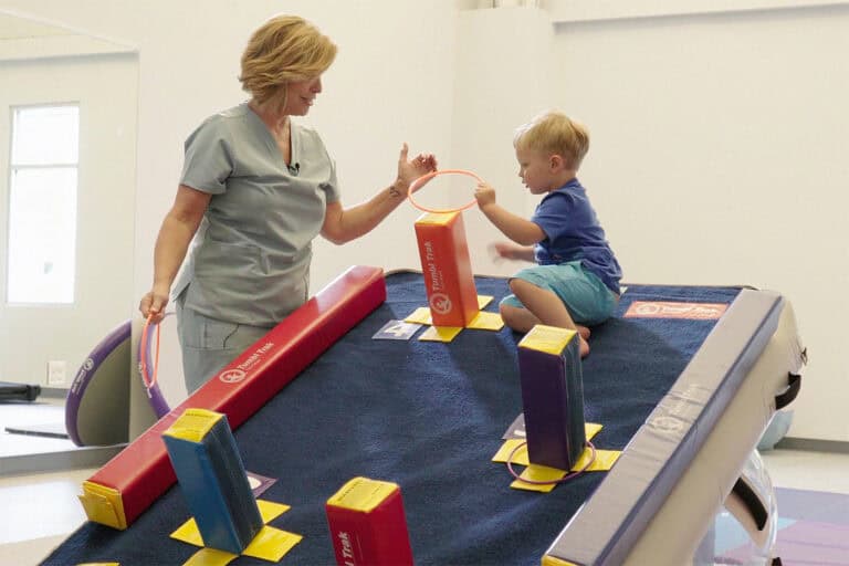 A photo showing a therapist and toddler client using Fun Sticks on a Carpet Wall Overlay.