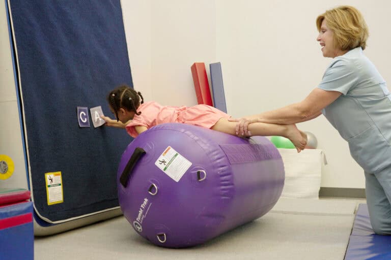 A photo showing a therapist and a client on an Air Barrel placing Sticky Manipulatives on a Carpet Wall Overlay.