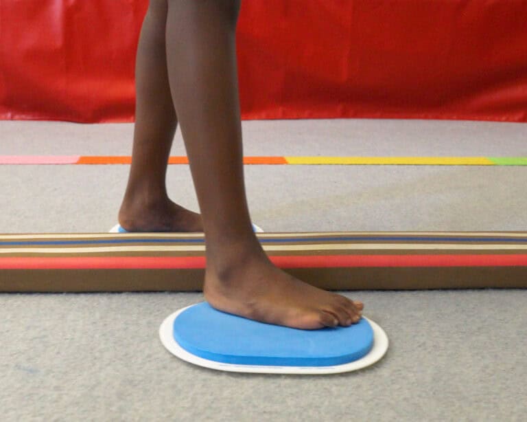 A photo showing a boy using large Sliders alongside a Laser Balance Beam.