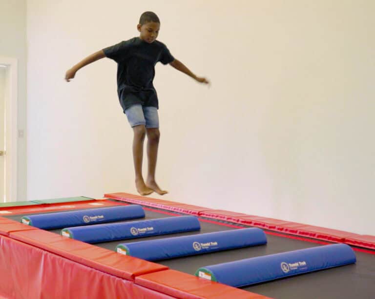 A photo of a boy on a Tumbl Trak jumping between a series of Half Rounds.