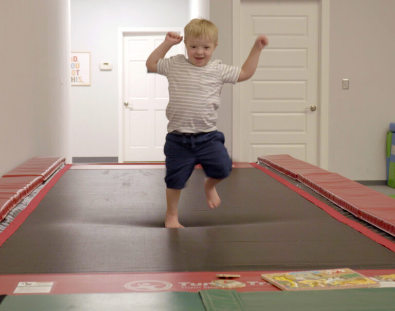 A photo of a boy joyfully walking on a Tumbl Trak.
