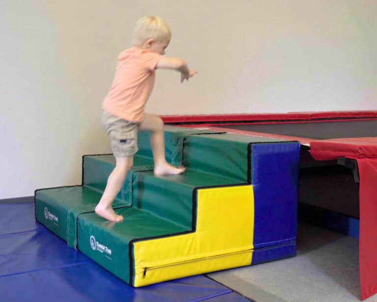 A photo of a boy climbing Tumbl Trak Steps in an occupational therapy clinic.