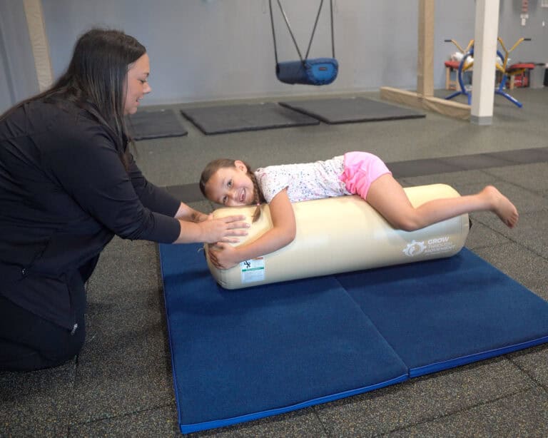A photo showing an occupational therapist working with a young client on an Air Bolster Mini.