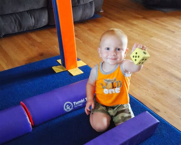 A photo of a boy on a carpet mat with Fun Sticks and Half Rounds.