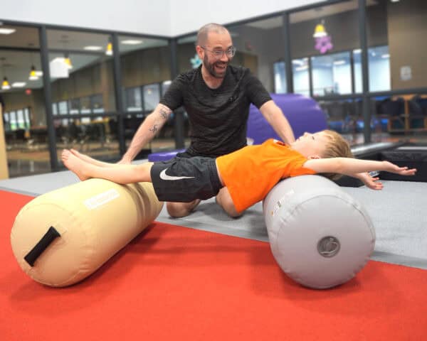 A therapist works with a client doing bridges on the Air Bolster Mini.