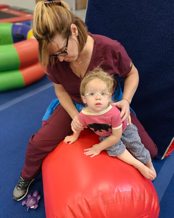 A photo of a therapist working with her client on an air barrel.